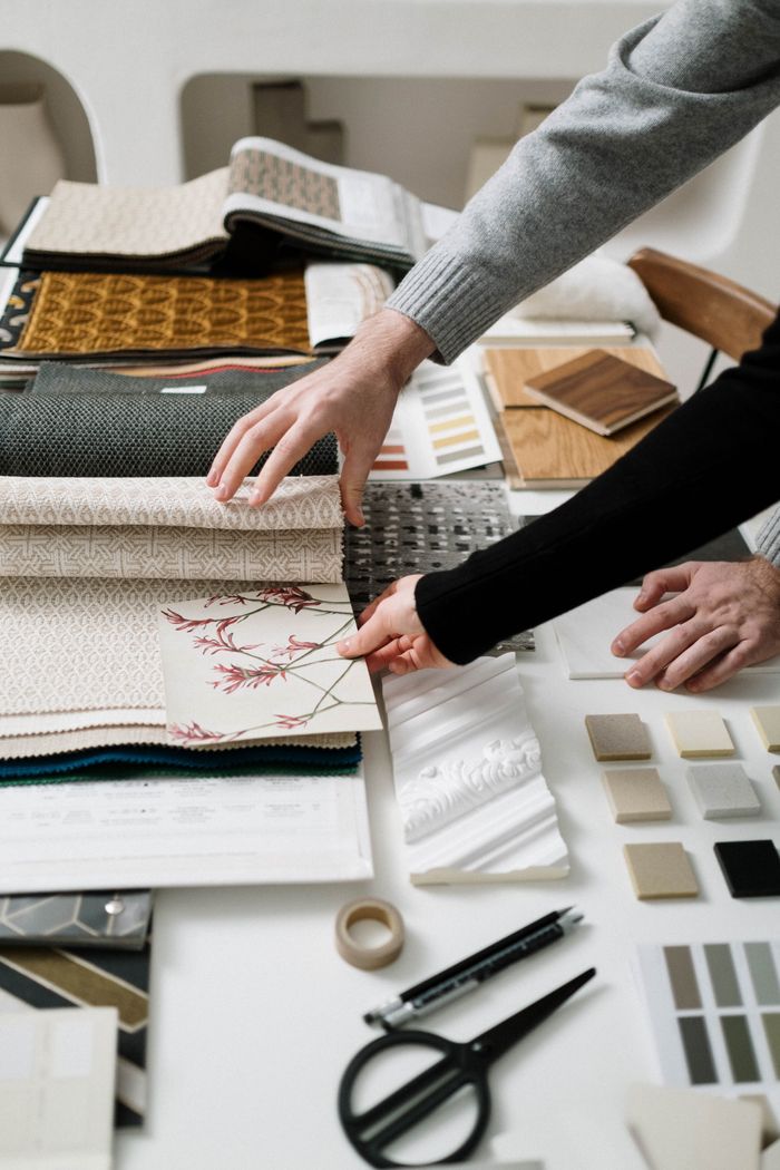 Close-up of hands selecting fabric patterns for interior design project.