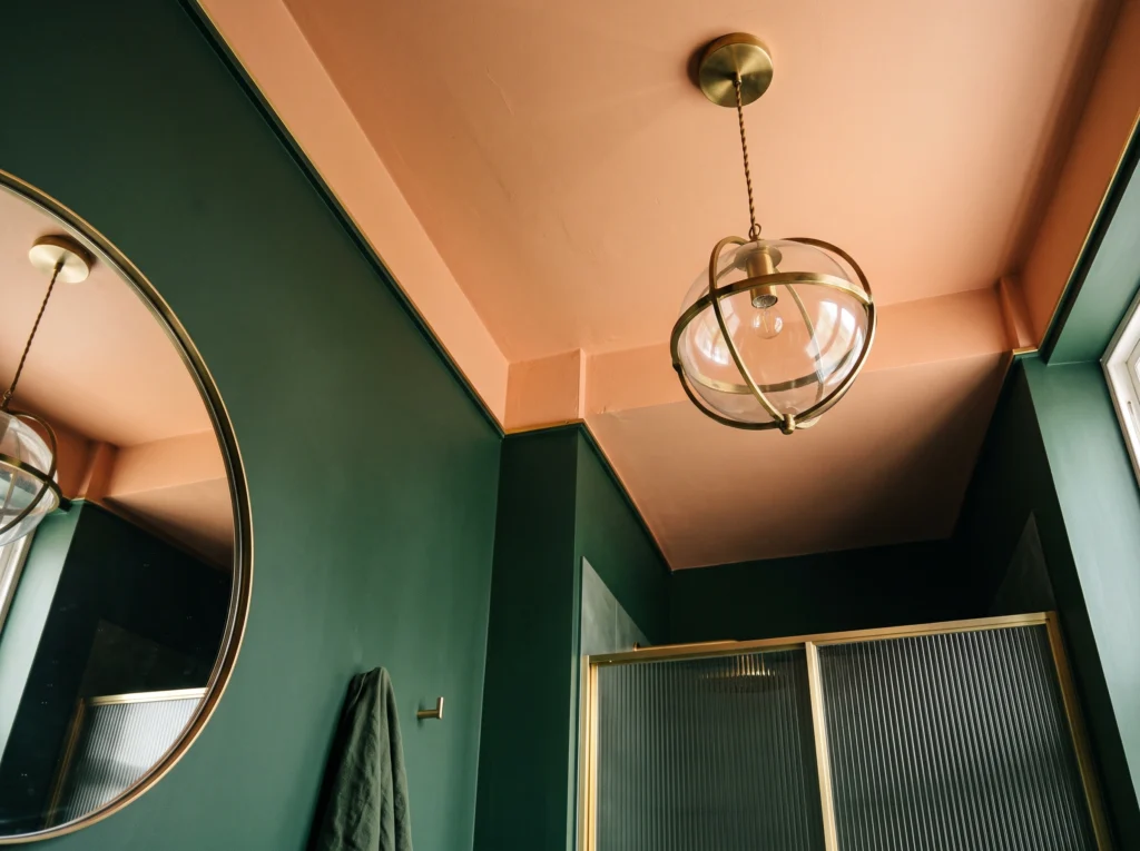 Deep olive green bathroom walls contrasting with a warm pale peach painted ceiling.